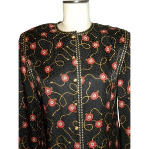May include: Black jacket with a repeating pattern of red and gold floral designs. The jacket has a round neckline and gold buttons down the front. The fabric has a subtle leopard print texture.