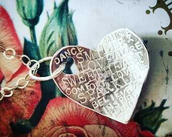 Necklace with positive words stamped on a handmade curved silver heart that's hung on a circle chain with handmade clasp. Perfect persent.