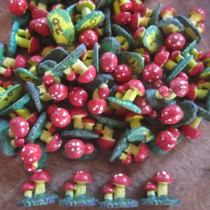 May include: A collection of small, hand-painted wooden mushrooms with red and white tops and green and yellow bases. Some of the mushrooms have numbers painted on them.