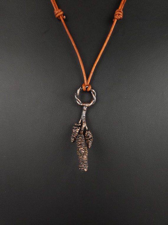 Real alder cones encased in copper through electroforming — nature literally becomes jewelry, no two are identical.