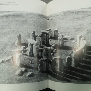 Puede incluir: Vista a&eacute;rea en blanco y negro de Stonehenge, un monumento prehist&oacute;rico en Inglaterra. La imagen muestra el c&iacute;rculo de piedra y el paisaje circundante. El texto dice: Vista a&eacute;rea de Stonehenge, mirando hacia el noroeste.