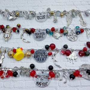 May include: Four silver charm bracelets with various charms, including guitars, wings, and pendants with text. The charms are accented with red, black, and clear beads. One bracelet features a yellow rubber duck charm.