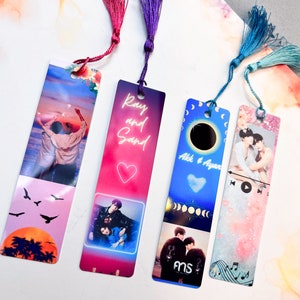 May include: Four colourful bookmarks with tassel accents. Each bookmark features a different design, including images of people, text, and graphics. The bookmarks have a rectangular shape and are made of a glossy material.