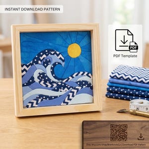 Könnte beinhalten: Ein Stoffkunstwerk in einem hellen Holzrahmen, das eine stilisierte Meereswelle und eine gelbe Sonne darstellt, mit blauen, marineblauen und weißen Zickzack- und Punktmustern. Enthält einen Stapel passender Stoffmuster und ein weißes Maßband.