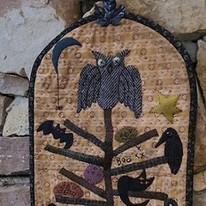 Könnte beinhalten: Ein brauner und schwarzer gesteppter Wandbehang mit einem Halloween-Baum mit einer Eule, Fledermäusen, Raben und Kürbissen. Der Baum ist mit einem Halbmond, einem Stern und den Worten "Boo" und "XX" verziert. Der Wandbehang misst 8,5 Zoll mal 16 Zoll.