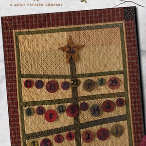 Peut inclure: Un modèle de courtepointe pour un calendrier de l'Avent représentant un sapin de Noël avec une étoile au sommet et des cercles numérotés pour chaque jour de décembre. Le modèle est intitulé "Calendrier de l'Avent" et est de "Primitive Pieces by Lynda".