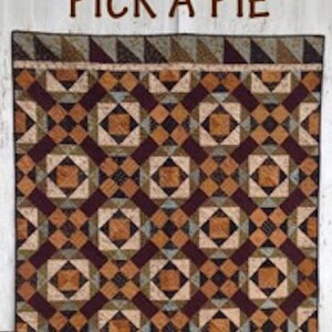 May include: A quilt pattern book titled "Pick a Pie" featuring a quilt with a geometric pattern in shades of brown, beige, and burgundy. The book cover also includes a pie, a rolling pin, and nuts.