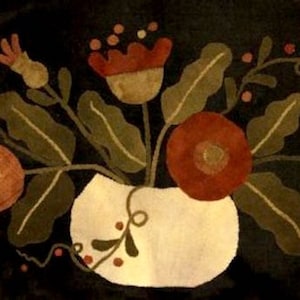 May include: A hand-stitched rug featuring a bouquet of red, orange, and brown flowers in a white vase. The flowers are surrounded by green leaves and vines against a dark brown background.