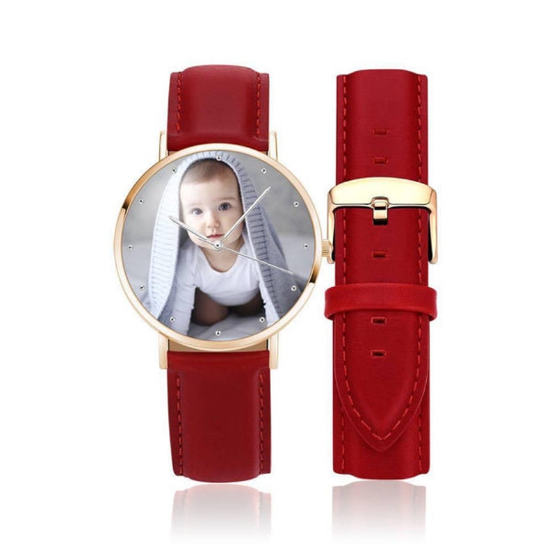 May include: A personalized wristwatch with a red leather band and a gold-colored case. The watch face features a photo of a baby. An extra red leather watch strap is included.