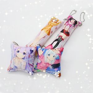 May include: Four colorful anime character pillow keychains. The keychains are made of soft fabric and feature different characters with pink, purple, blue, and yellow accents.