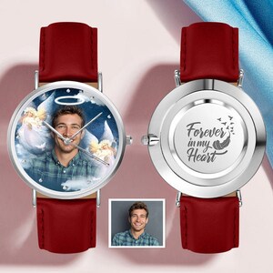 May include: Two silver watches with red leather straps. One watch face features a photo of a person with angel wings and a halo. The other watch face has the text "Forever in my Heart" with a feather and birds.