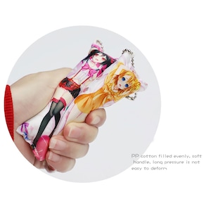May include: A colorful keychain featuring two anime characters. The keychain is made of soft, plush fabric and has a metal ring for attaching to keys or bags.