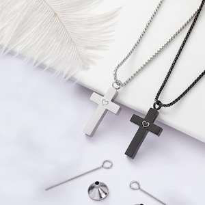 May include: Two silver and black cross necklaces with a small heart engraved on each cross. The necklaces come with a small funnel and a tool to insert ashes into the cross.