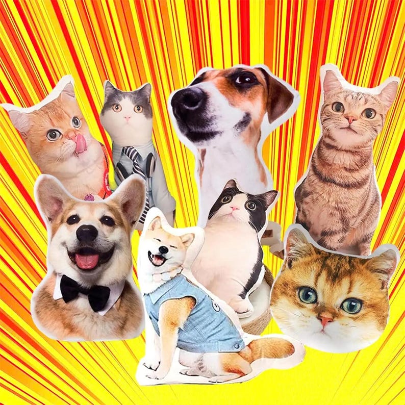 May include: A collection of plush animal pillows featuring various cat and dog breeds. The pillows are in the shape of the animals' heads and bodies, with detailed facial features and some wearing accessories like bow ties and denim jackets. The background is a yellow and orange burst.