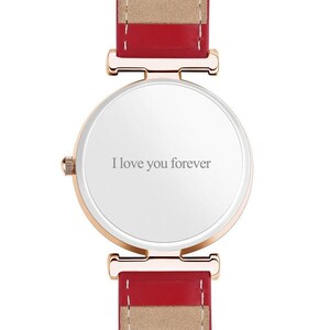 May include: A rose gold watch with a white face and a red and tan leather band. The watch face has the inscription "I love you forever" in gray lettering. The watch band is approximately 0.75 inches wide.