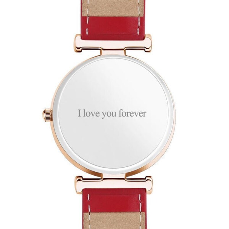 May include: A rose gold watch with a white face and a red and tan leather band. The watch face has the inscription "I love you forever" in gray lettering. The watch band is approximately 0.75 inches wide.