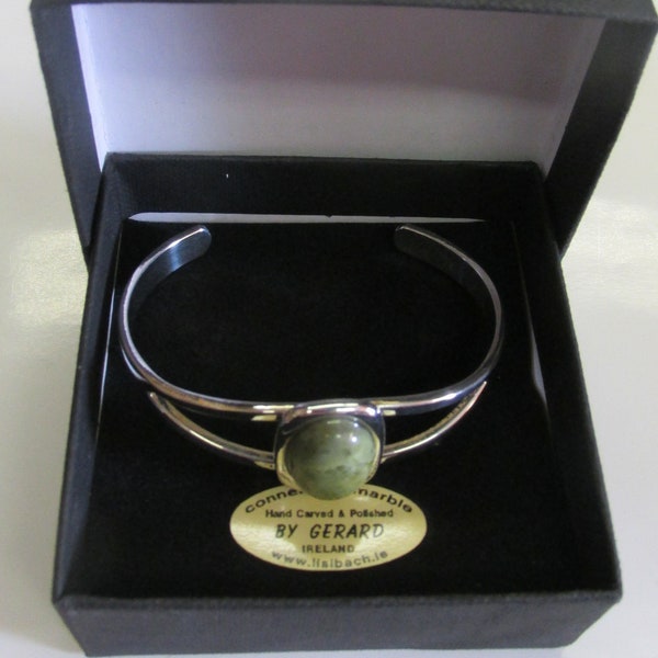 May include: A silver bangle bracelet with a green Connemara marble stone set in the center. The bracelet is in a black box with a gold label that reads "Hand Carved & Polished BY GERARD IRELAND www.tlsibach.ie"