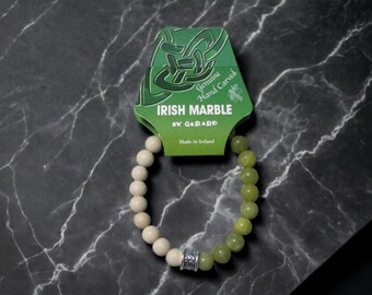 May include: A green and white marble bracelet with a silver charm. The bracelet is made in Ireland and is hand-carved. The packaging says "Genuine Hand Carved Irish Marble by Gerard".