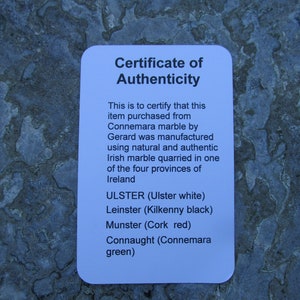 May include: A white rectangular certificate of authenticity with black text stating it certifies an item purchased from Connemara marble by Gerard was manufactured using natural and authentic Irish marble quarried in the four provinces of Ireland.
