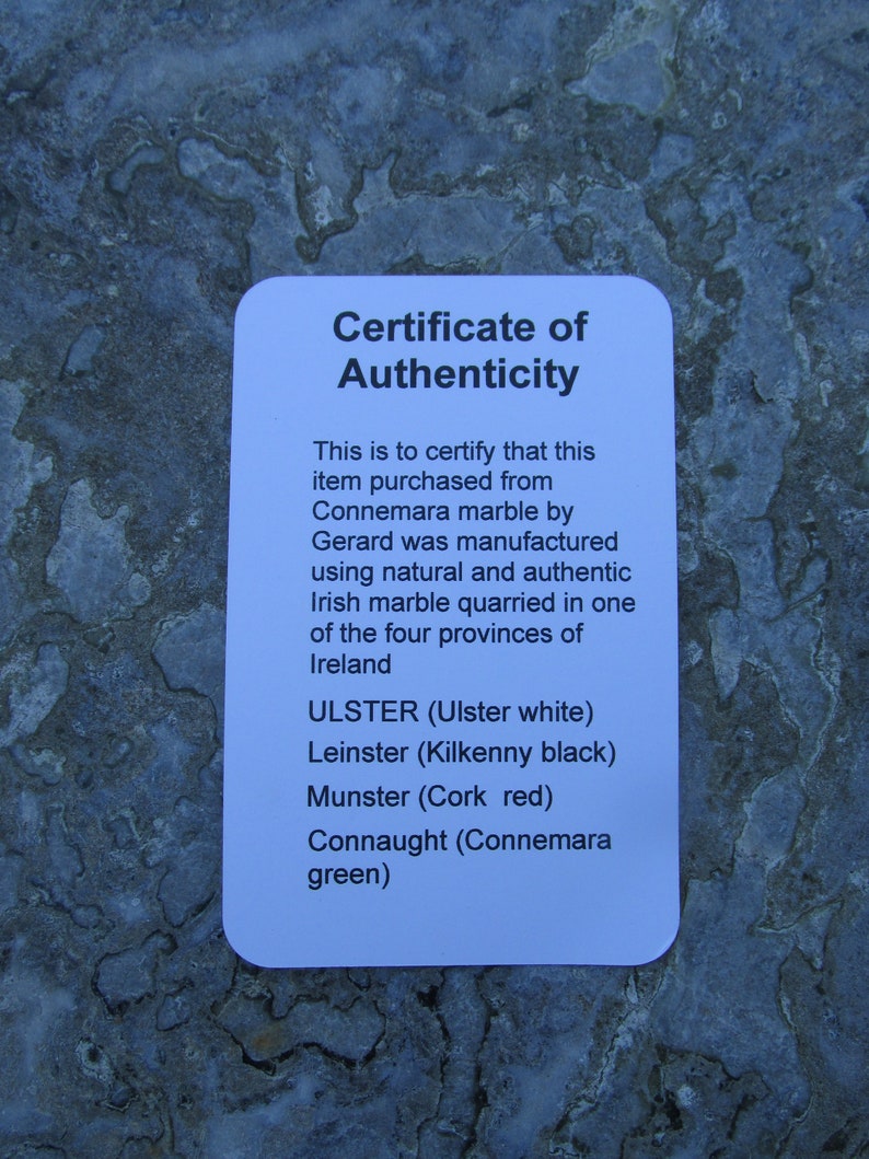May include: A white rectangular certificate of authenticity with black text stating it certifies an item purchased from Connemara marble by Gerard was manufactured using natural and authentic Irish marble quarried in the four provinces of Ireland.