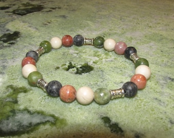 May include: A bracelet made of various colored beads, including green, white, pink, and black. The beads are separated by silver spacers.