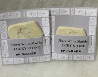 May include: Two white marble lucky stones with a shamrock design. Each stone is packaged in a white card with the text "Ulster White Marble Lucky Stone by Gerard".