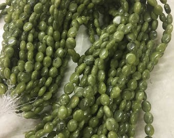 Può includere: Un filo di perline ovali di giada verde. Le perline sono lisce e lucidate, con un aspetto naturale e terroso.