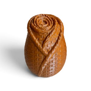 May include: A brown, egg-shaped object with a textured surface that mimics a woven basket pattern. The top section features a spiraled, layered design resembling a rosebud, with raised, smooth ridges forming the petals and leaves.