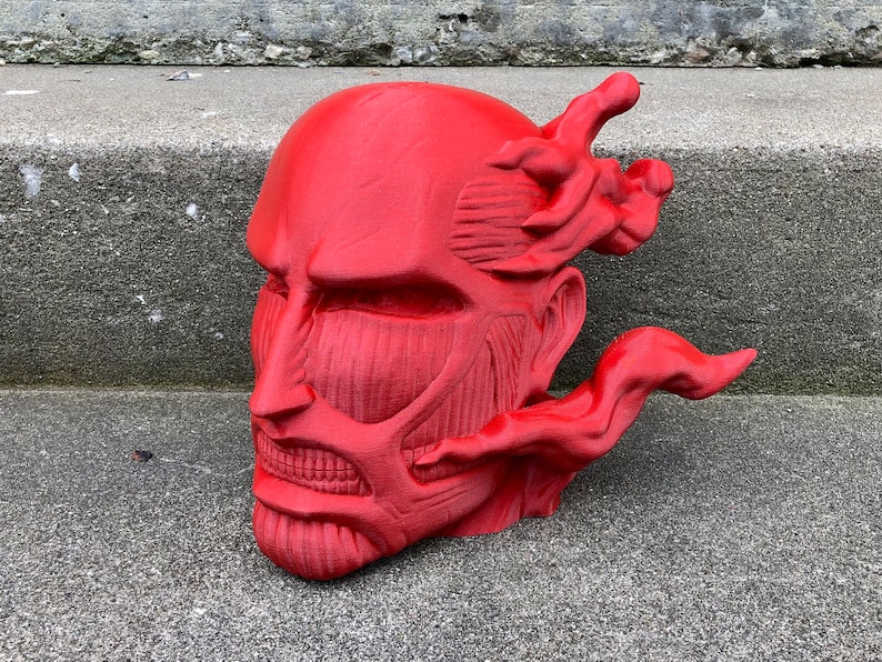 May include: A red 3D printed bust of a character with a detailed muscular face and a flowing red mane. The bust is a popular anime character.