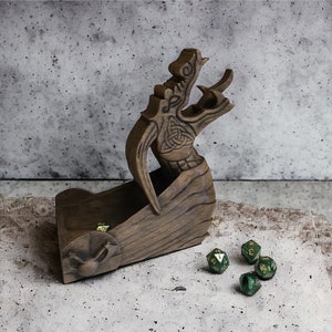May include: A wooden dragon head dice tower with a carved design. The tower is holding four green dice with gold accents.