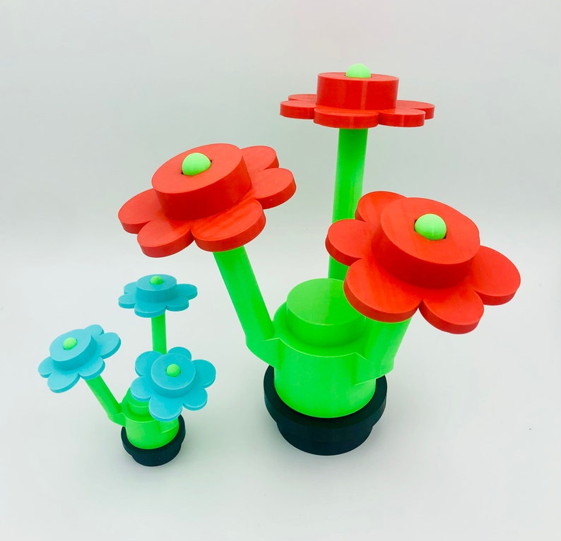 May include: A set of three red and blue flower-shaped planters with green stems. The planters are arranged in a cluster and have a black base.