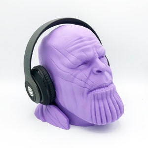Può includere: Busto di Thanos di colore viola stampato in 3D con cuffie wireless nere.