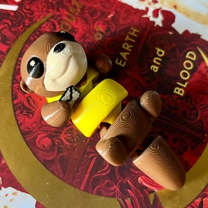 Decoração de estante de lontra mensageiro - brinquedo de lontra articulado com colete amarelo e carta - decoração de livro impressa em 3D inspirada em CC