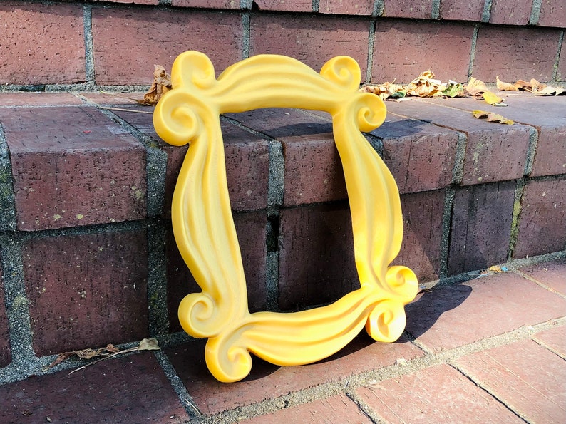 May include: A yellow plastic frame with a unique design, resembling a picture frame from the popular TV show "Friends".