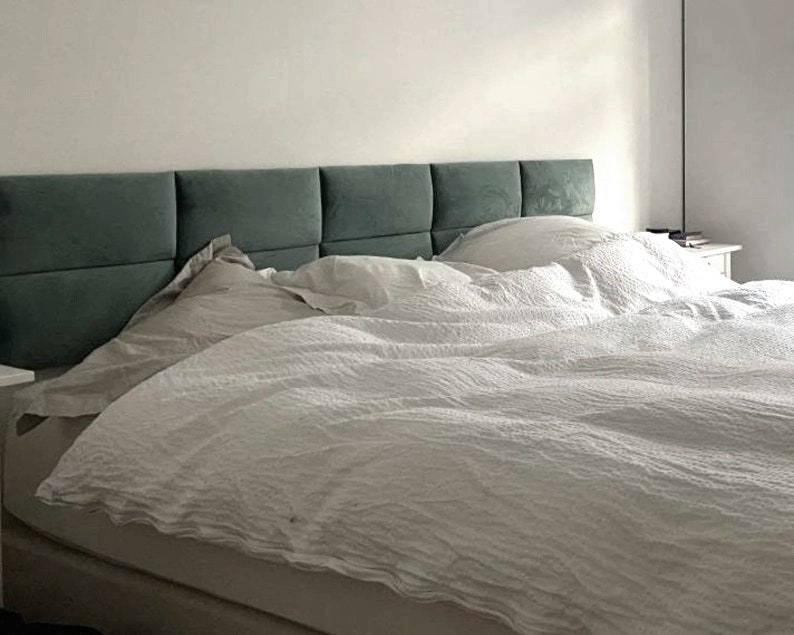 May include: A white bed with a teal headboard and white bedding. The headboard is made of multiple panels.