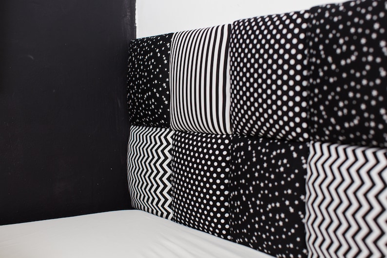 Puede incluir: Cuadrados de tela con patrones en blanco y negro cosidos juntos para crear una cabecera de cama. La cabecera est&aacute; hecha de diferentes patrones, incluyendo estrellas, rayas, lunares y zigzags.