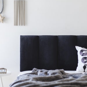 K&ouml;nnte beinhalten: Ein schwarzes, gestepptes Kopfteil mit einem wei&szlig;en Kissen mit einem schwarzen Schlangenmuster. Eine graue Decke liegt &uuml;ber dem Bett.