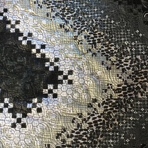 May include: A black and white quilt with a geometric pattern. The quilt is made of different fabrics with a variety of textures. The quilt is quilted with a variety of stitches.