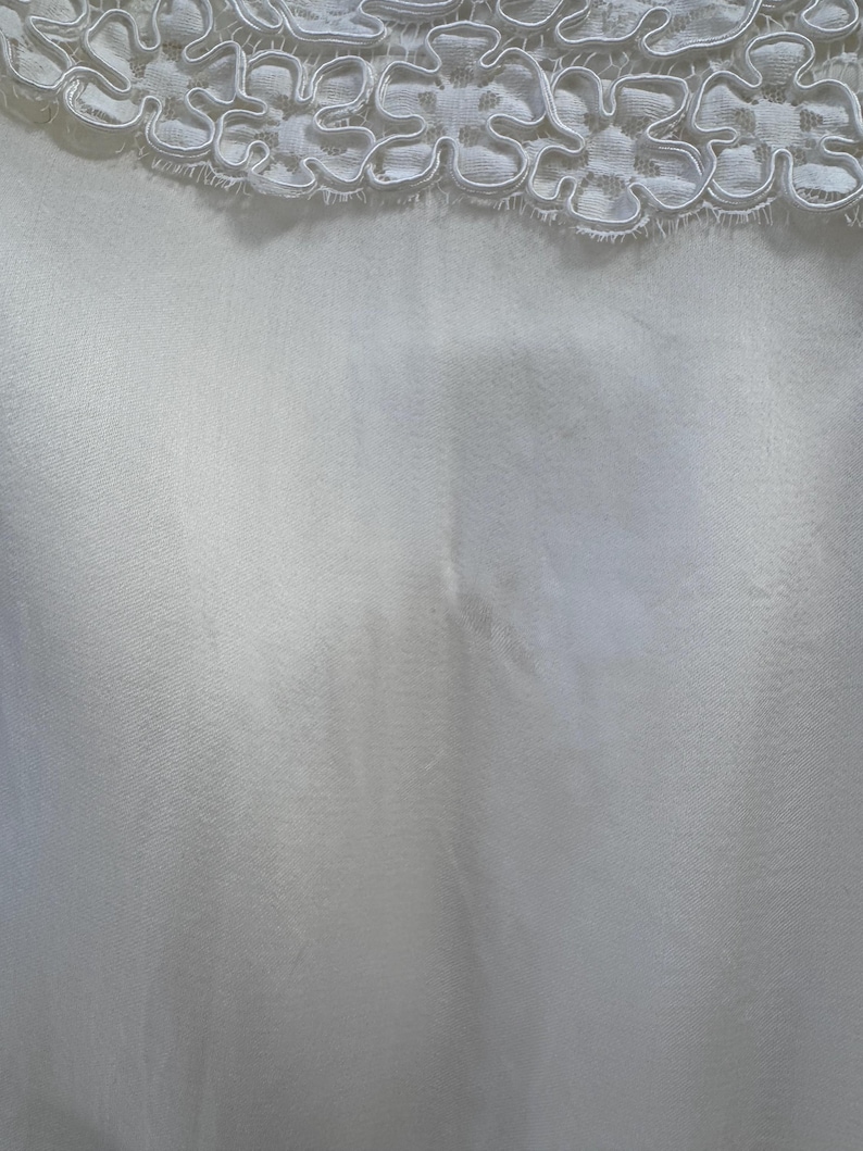 May include: White satin fabric with a white lace trim at the top.