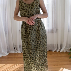 Pu&ograve; includere: Un abito maxi senza maniche dorato e verde con un motivo geometrico. L'abito ha un corpetto aderente e una gonna fluida.