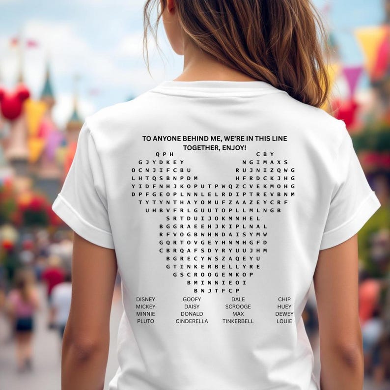 Pode incluir: Camiseta branca com um jogo de palavras em forma de cora&ccedil;&atilde;o e o texto "TO ANYONE BEHIND ME, WE'RE IN THIS LINE TOGETHER, ENJOY!". O jogo inclui nomes de personagens da Disney.