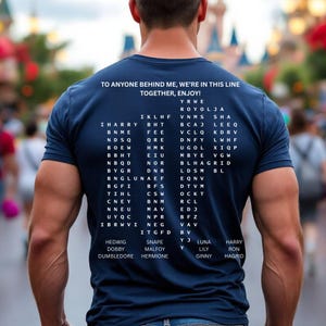 May include: Navy blue t-shirt with white text. The shirt reads "TO ANYONE BEHIND ME, WE'RE IN THIS LINE TOGETHER, ENJOY!" and features a list of names and codes. A casual wear item.