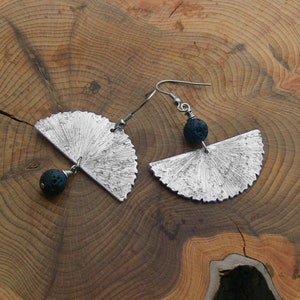 Può includere: Un paio di orecchini d'argento con un design a forma di ventaglio e perline di lava nera.