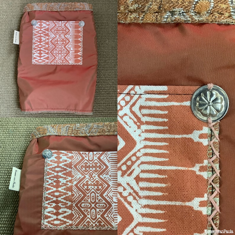 Puede incluir: Una bolsa de tela de color &oacute;xido con un patr&oacute;n geom&eacute;trico blanco. La bolsa tiene un peque&ntilde;o bolsillo con un patr&oacute;n geom&eacute;trico blanco y un bot&oacute;n plateado. La bolsa tiene una etiqueta que dice "Kussen van Paula".