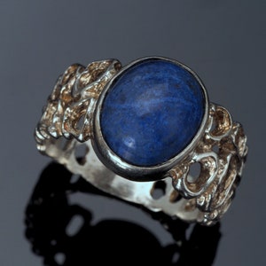 May include: A silver ring with a blue gemstone set in a textured band.