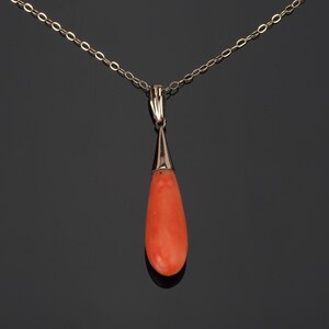 Pu&ograve; includere: Un ciondolo in corallo arancione a forma di goccia sospeso a una delicata catenina d'oro. La pietra di corallo liscia e lucida &egrave; incastonata in una semplice capsula d'oro che si collega alla catena a maglie sottili, creando un gioiello elegante.