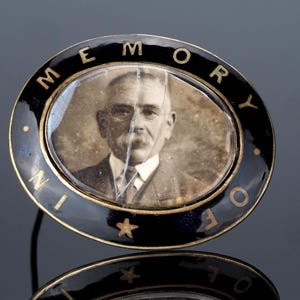Victorian Mourning brooch; with black enamel and In Memory Of text. Has picture and glass front is cracked