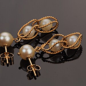 May include: A pair of gold earrings with a twisted rope design and white pearls. The earrings have a post back closure.