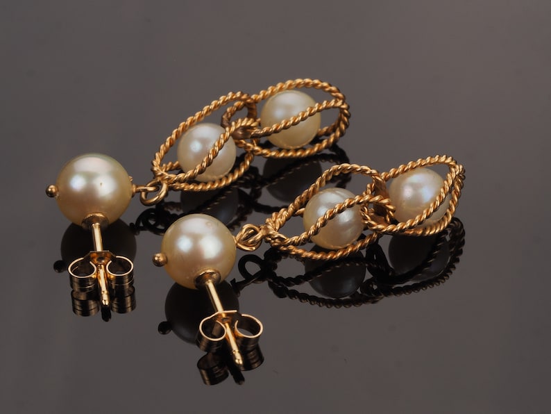 May include: A pair of gold earrings with a twisted rope design and white pearls. The earrings have a post back closure.