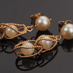 May include: A pair of gold earrings with pearl drops. Each earring features a twisted gold wire design with three pearls.